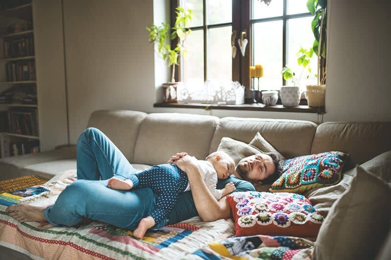 Vater und Baby schlafen auf Couch