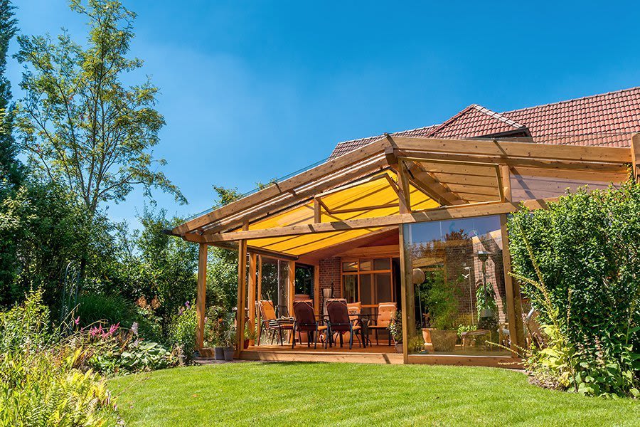 Wintergarten aus Holz mit Sonnenschutz Übergang zu Garten