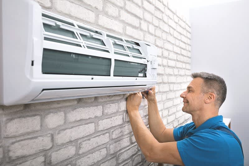 Monteur arbeitet an einer Klimaanlage, die an der Wand installiert ist