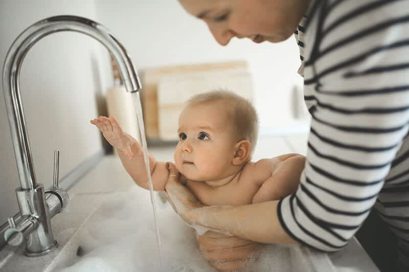 Baby badet im Waschbecken