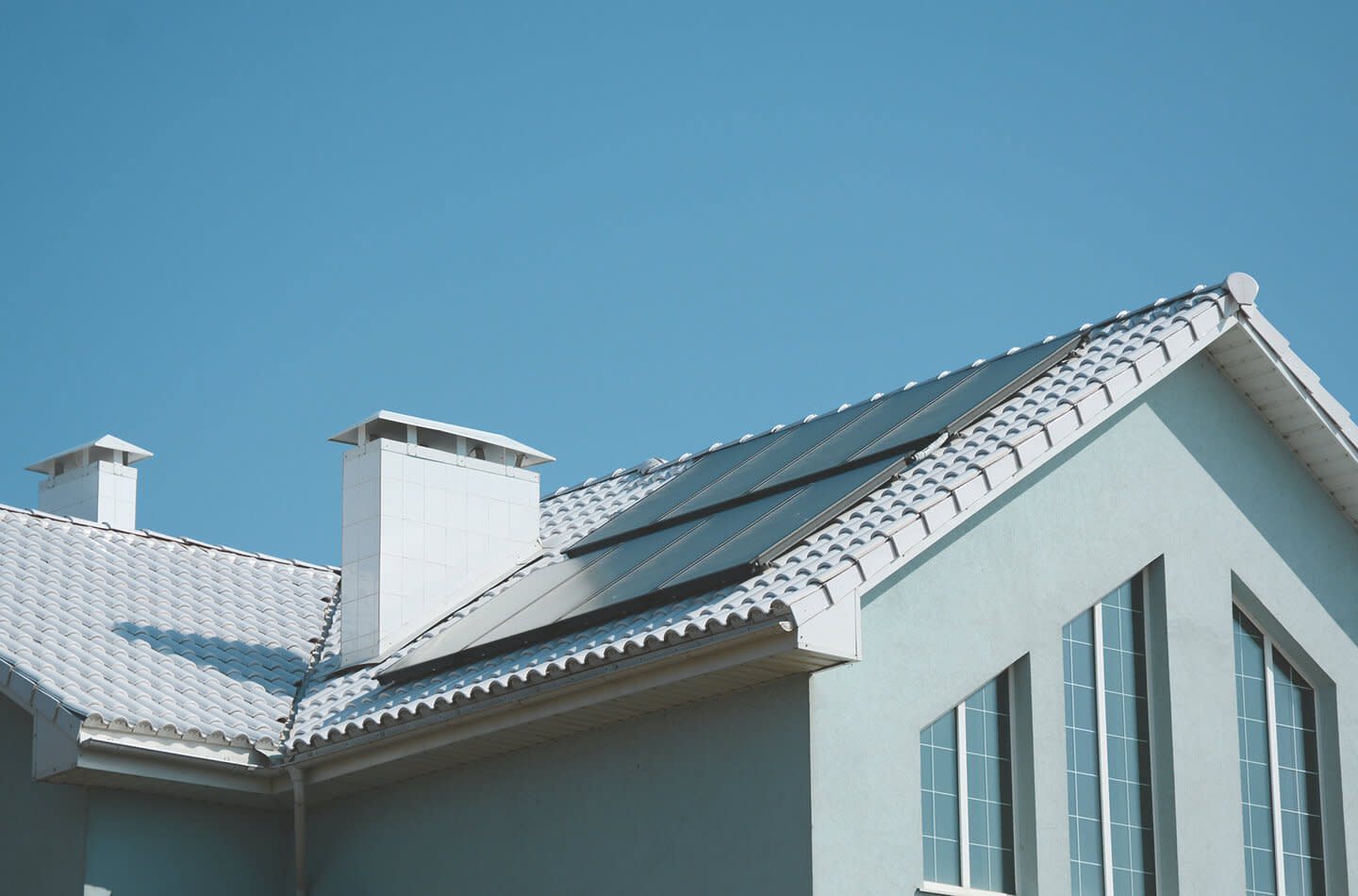 Blaues Haus mit hellem Dach und einer Solaranlage