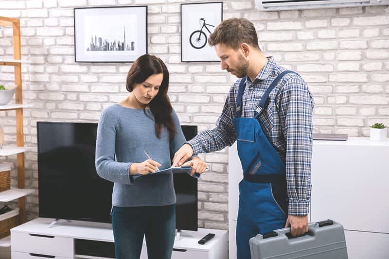 Frau unterschreibt Abnahmeprotokoll eines Handwerkers, der neben ihr steht