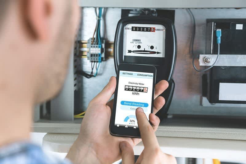 Mann liest mit Handy Strom vom Stromzähler ab