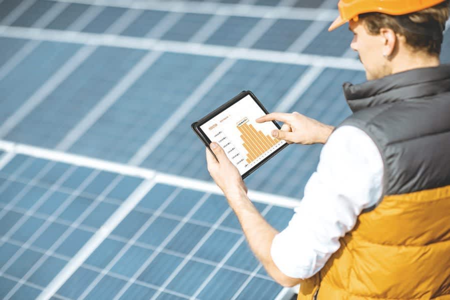 Handwerker mit Tablet vor Photovoltaikanlage