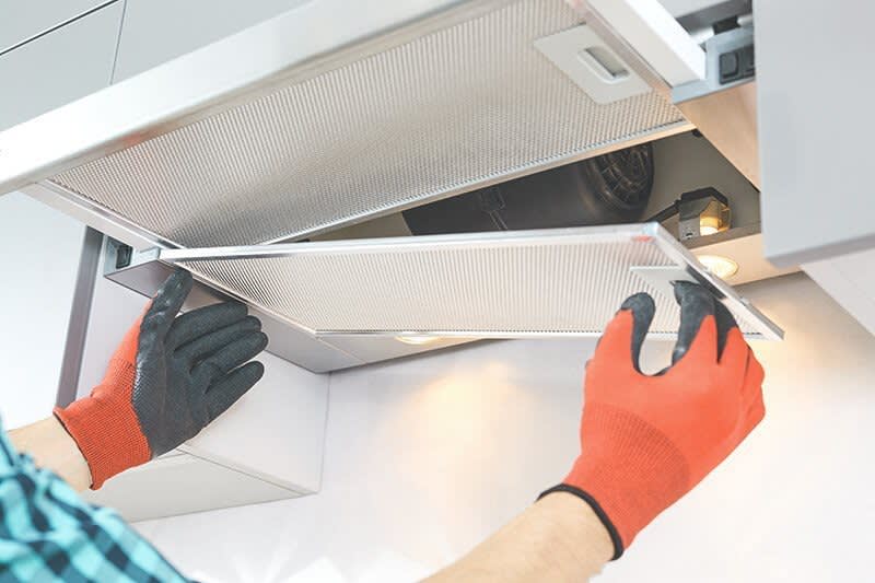 Mann nimmt Metallfilter an Dunstabzugshaube ab