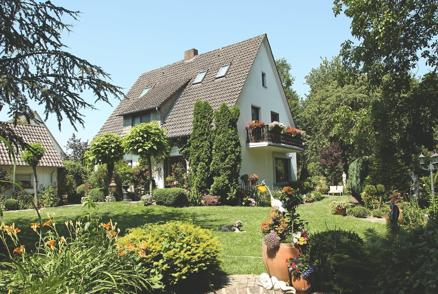 Einfamilienhaus mit weißer Fassade und Balkon in Garten