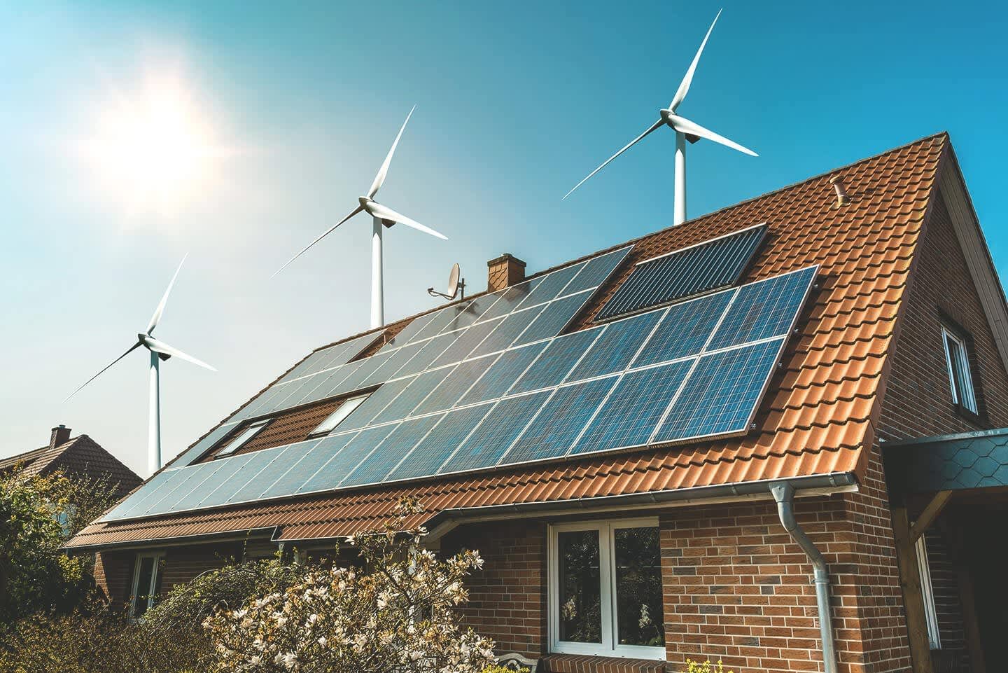 Haus mit Solaranlage und Windrädern