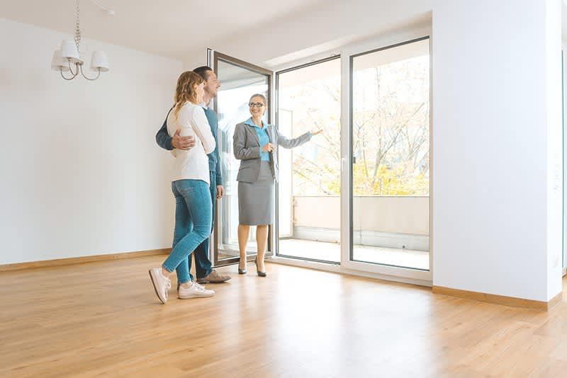 Makler besichtigt mit Pärchen ein Haus