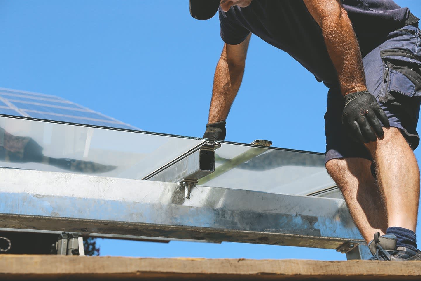 Handwerker montiert Terrassenüberdachung aus Glas