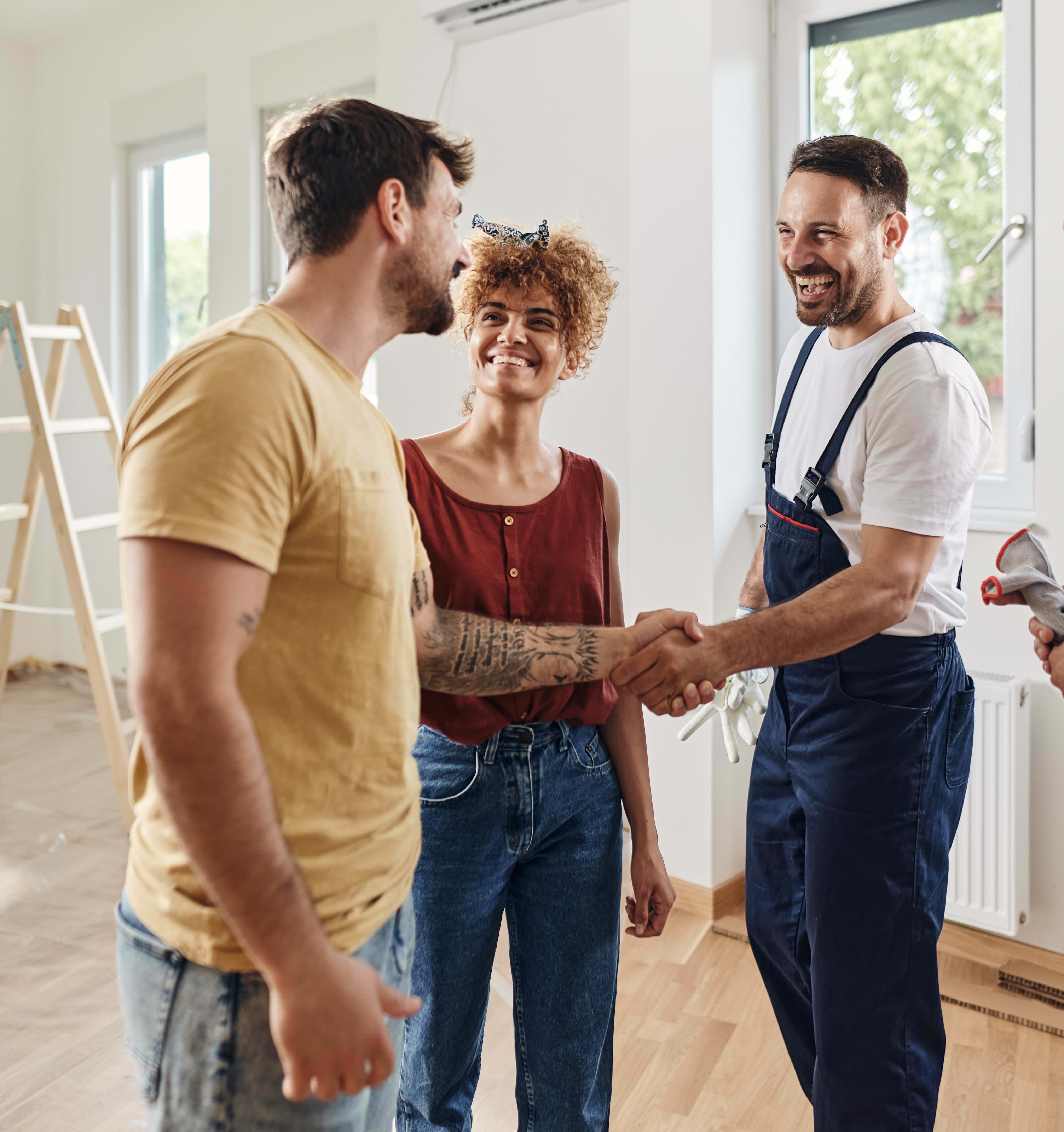 Hauseigentümer und Handwerker geben sich nach einem erfolgreichen Projekt zufrieden die Hände.