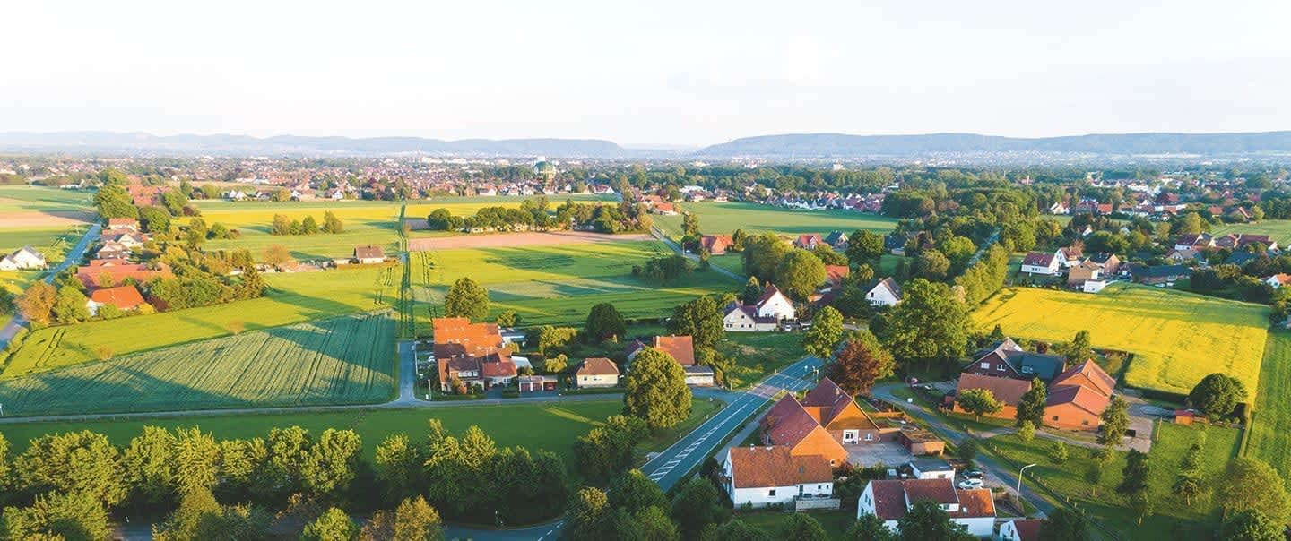 Luftaufnahme einer Ortschaft in Deutschland mit Wiesen bei Sonnenschein