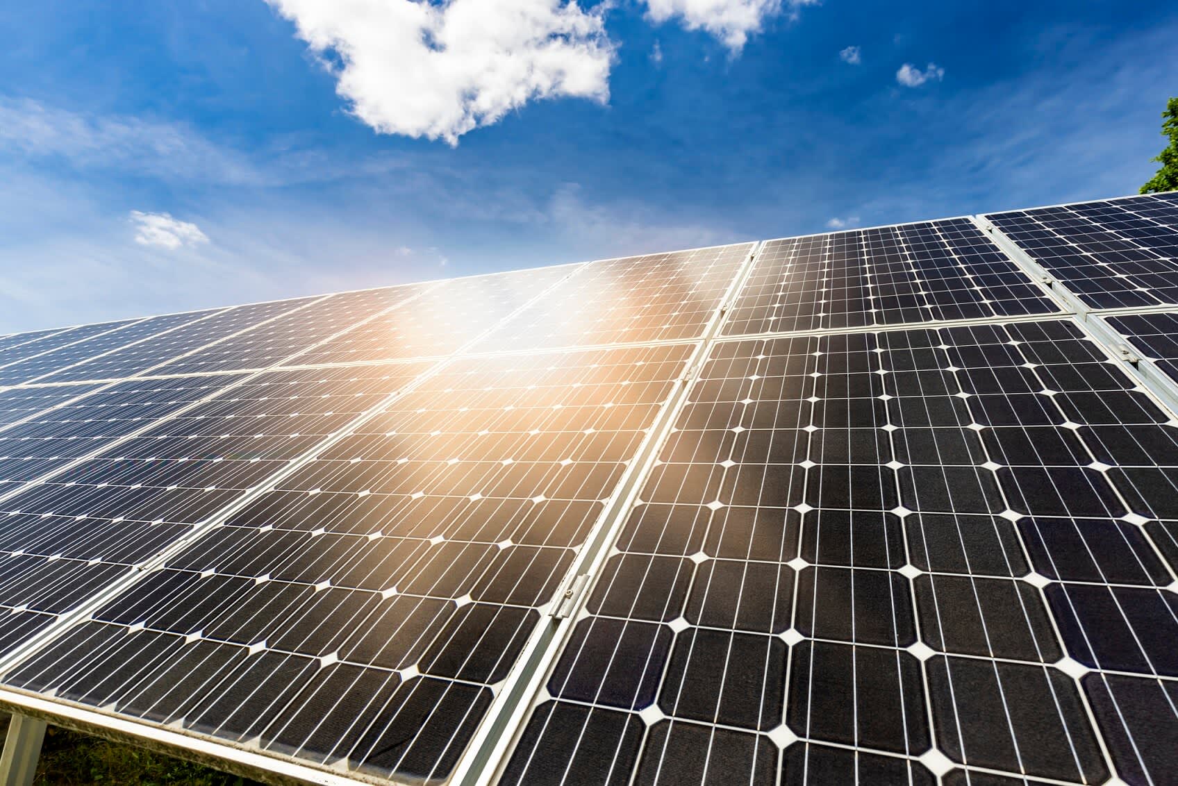 Solarmodule, auf die die Sonne scheint, auf einem Hausdach unter blauem Himmel