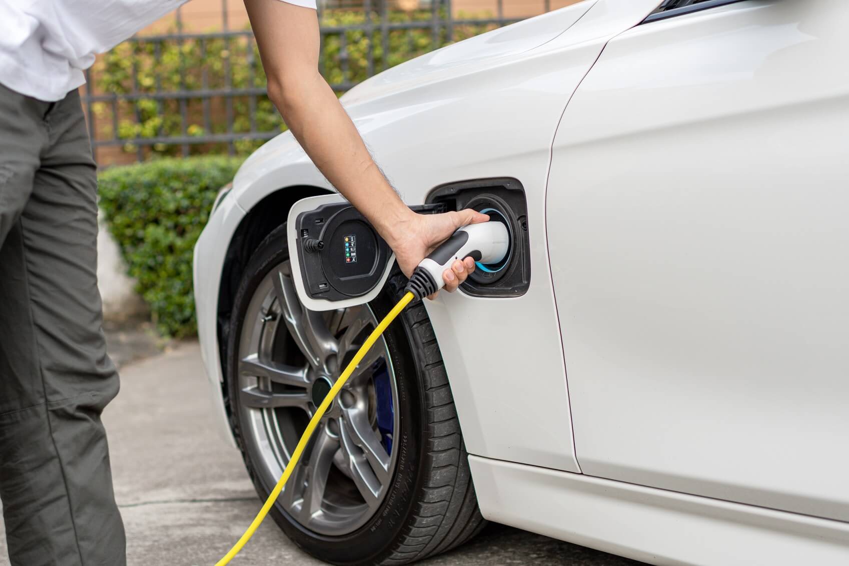 Mann lädt sein Elektroauto vor seinem Haus