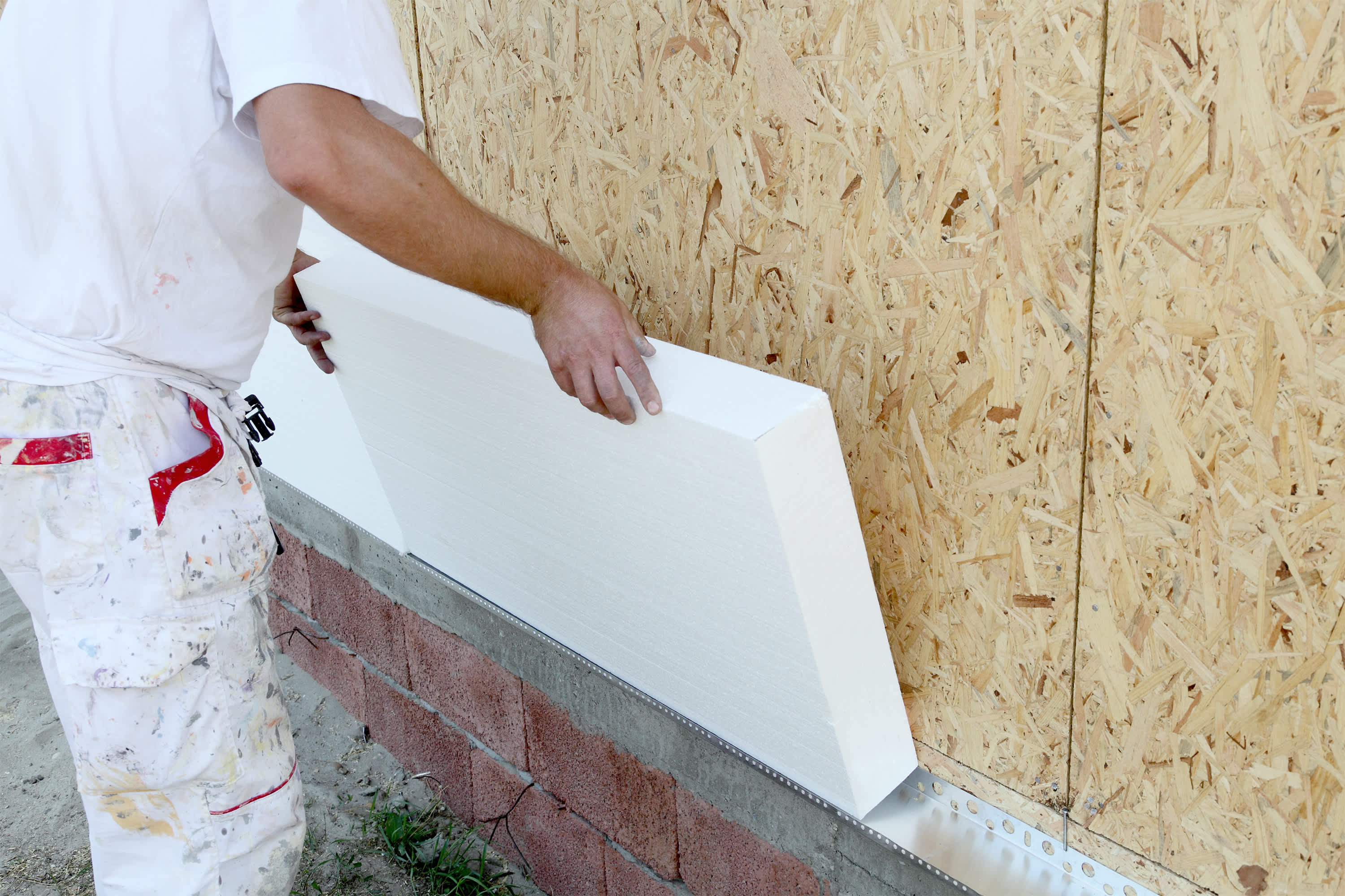 Handwerker bringt Dämmplatte an einer Hausfassade an