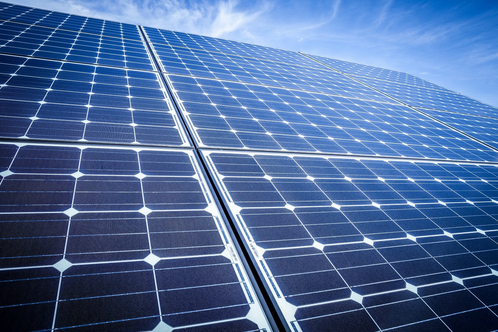 Nahaufnahme mehrerer Photovoltaikmodule auf einem Schrägdach bei blauem Himmel mit einigen Wolken