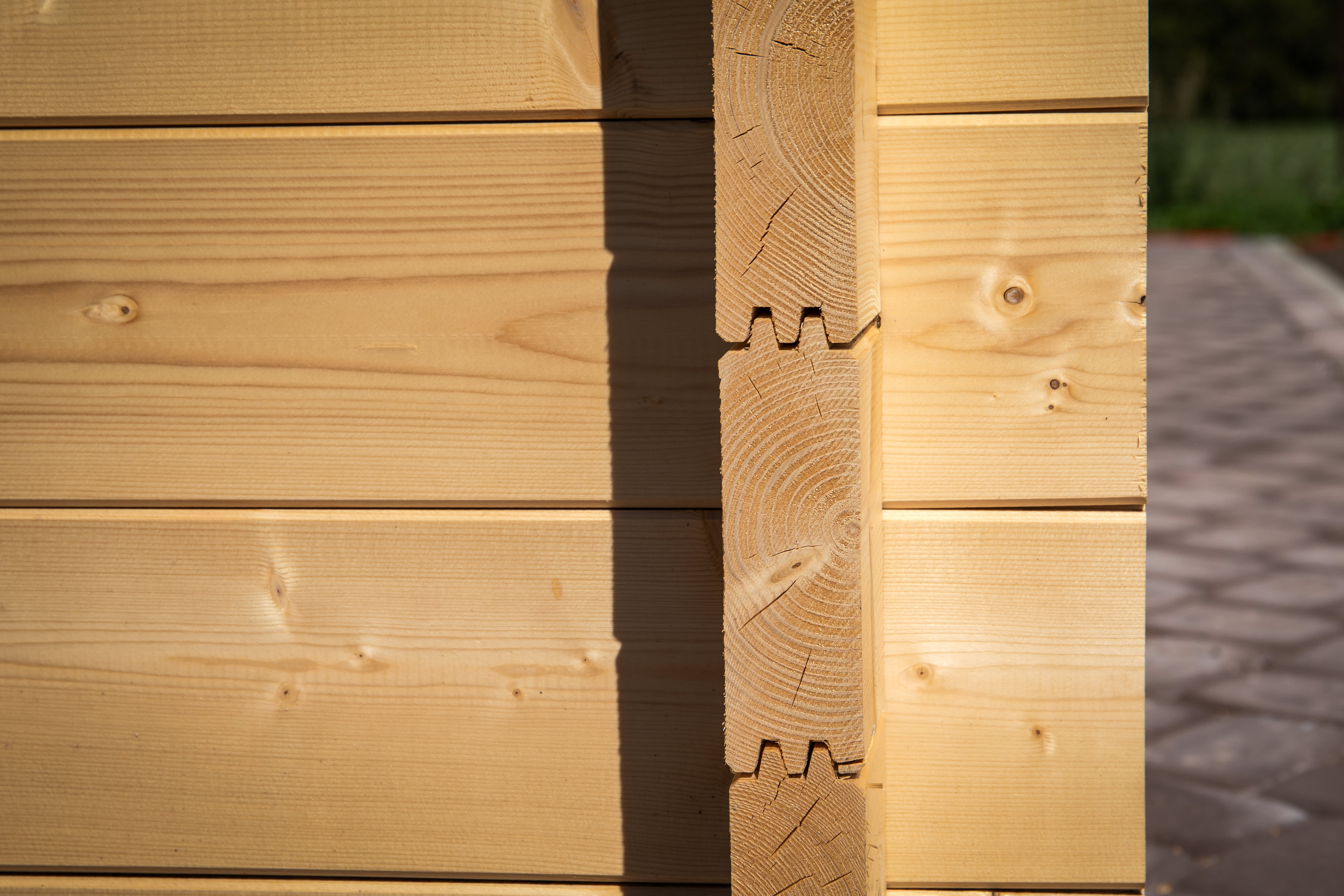 Ecke einer Holzwand mit verzahnten Holzbalken in Blockbohlenbauweise gefertigt.