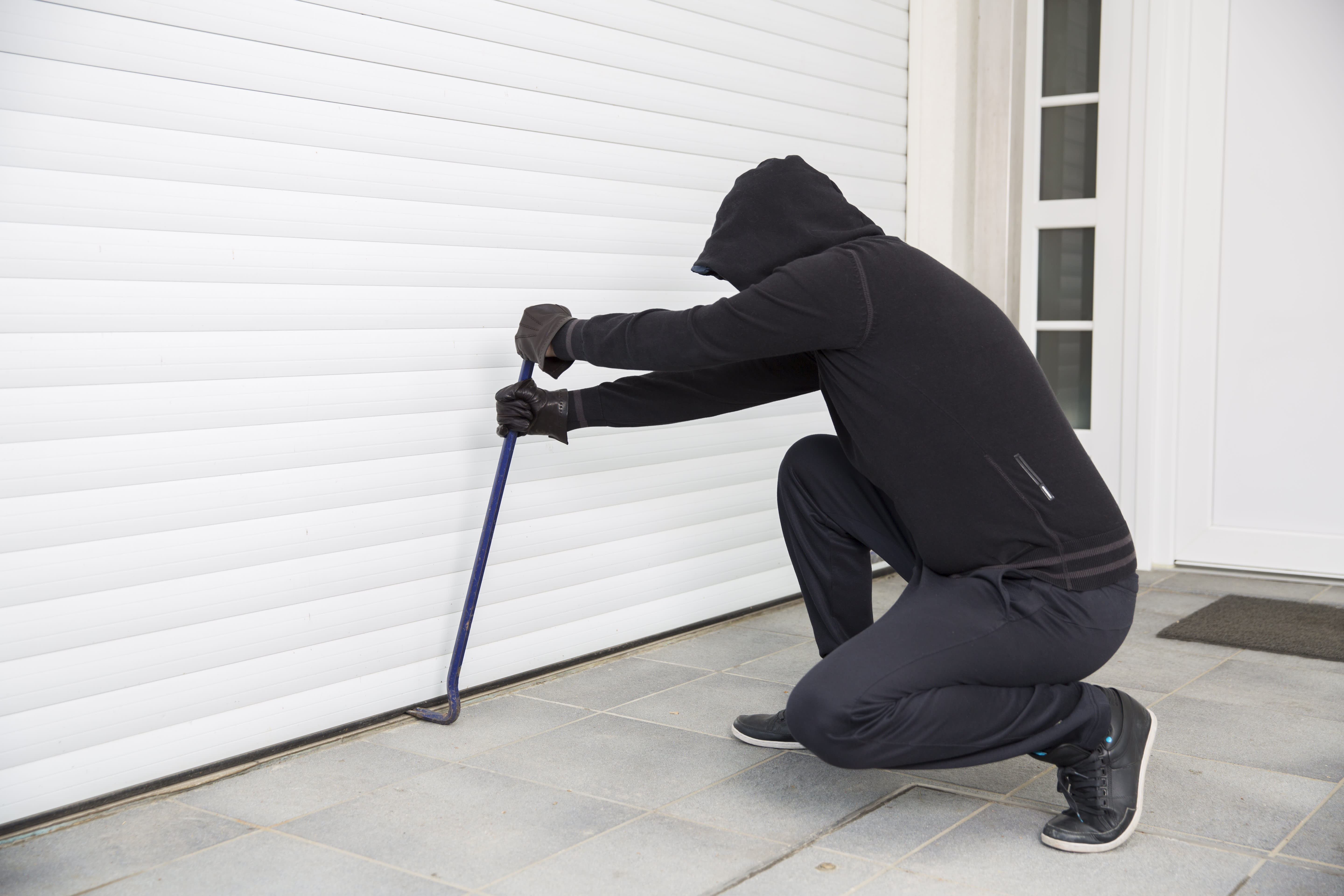 Einbrecher bricht mit einem Stemmeisen in eine Garage ein