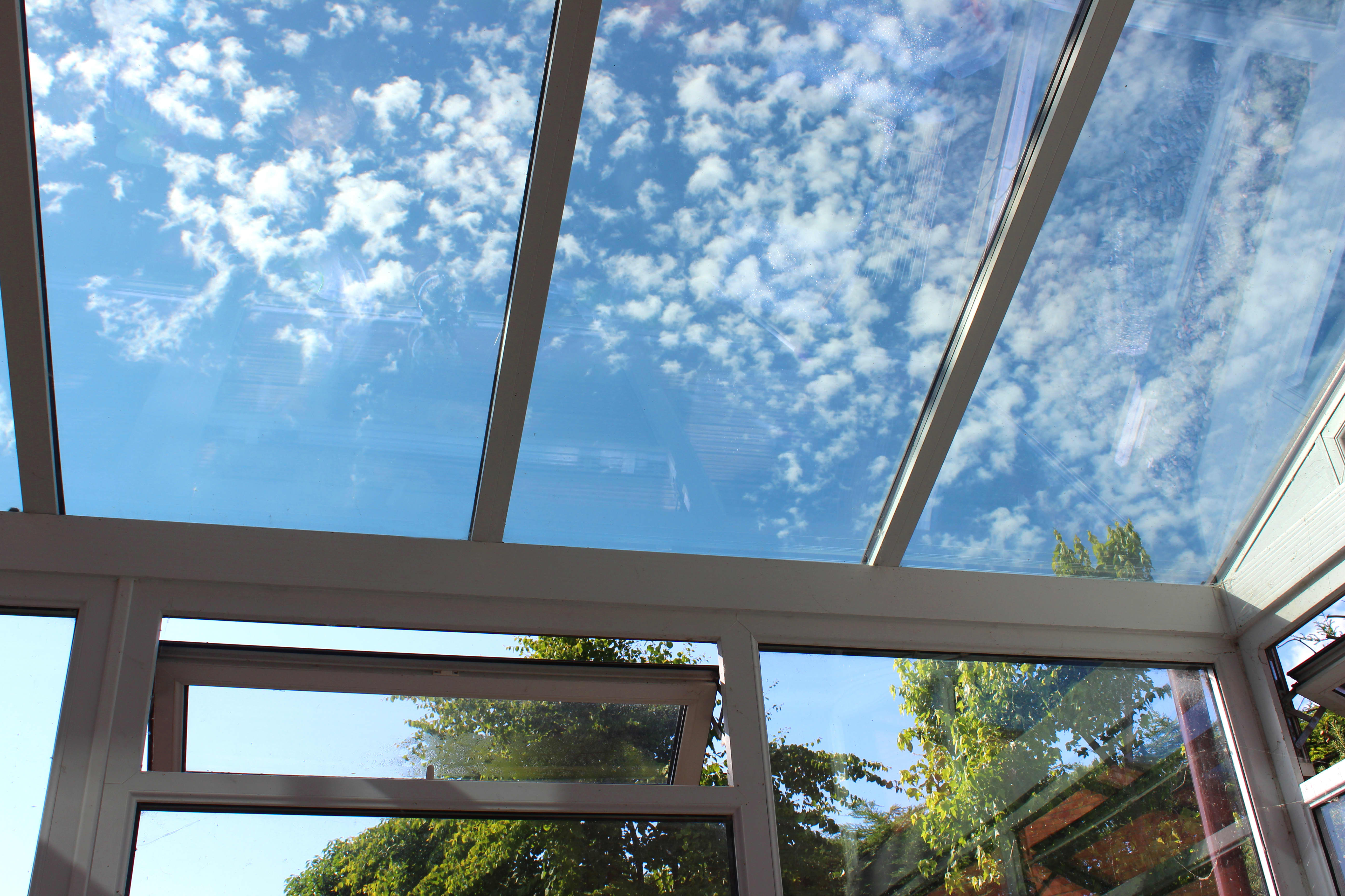 Freier Blick in den Himmel unter einer Terrassenüberdachung aus Glas.