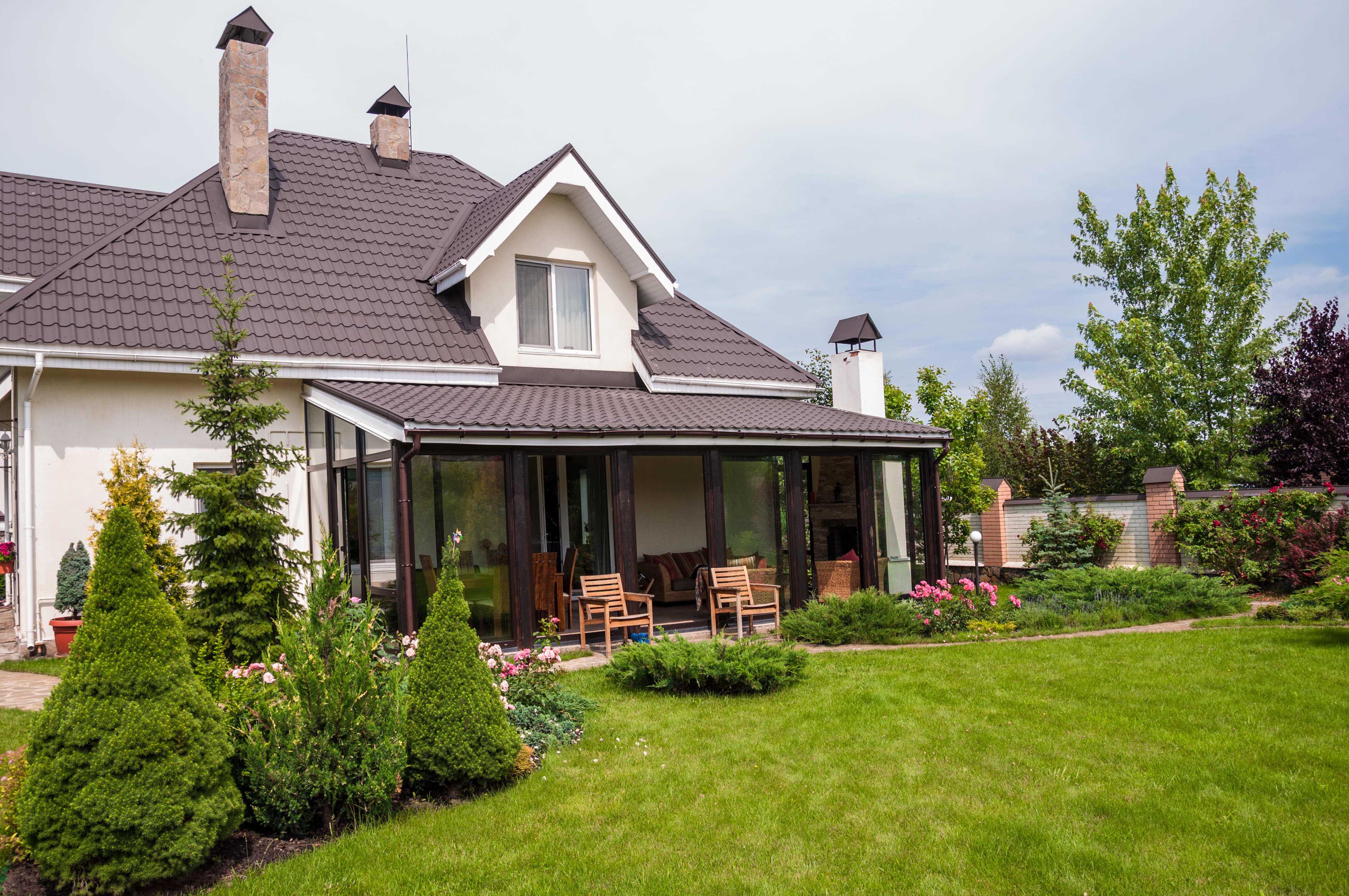 Terrassenüberdachung mit Ziegeln vor einem Einfamilienhaus mit Garten