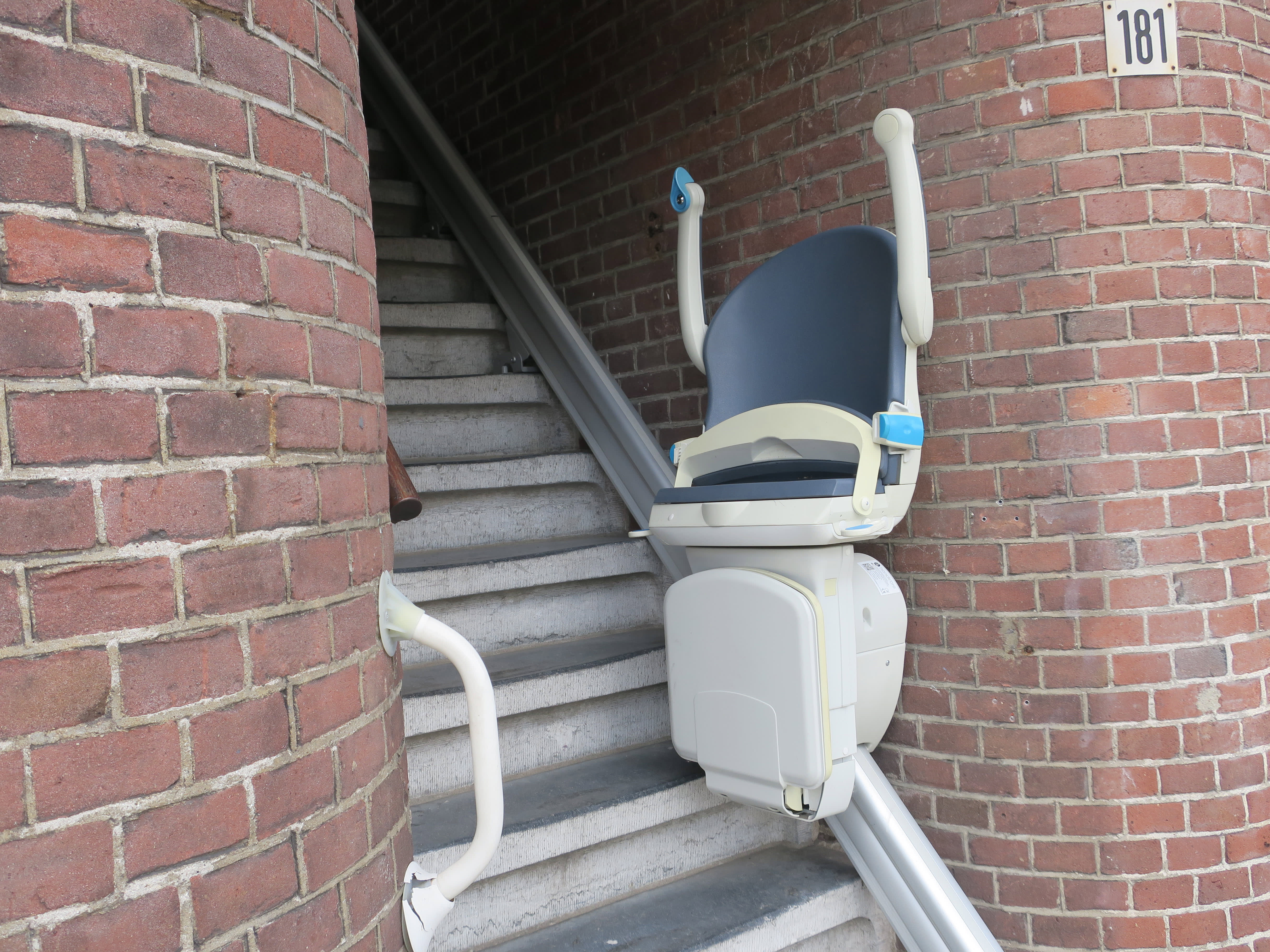 Hochgeklappter Sitzlift an einer schmalen Treppe im Außenbereich.