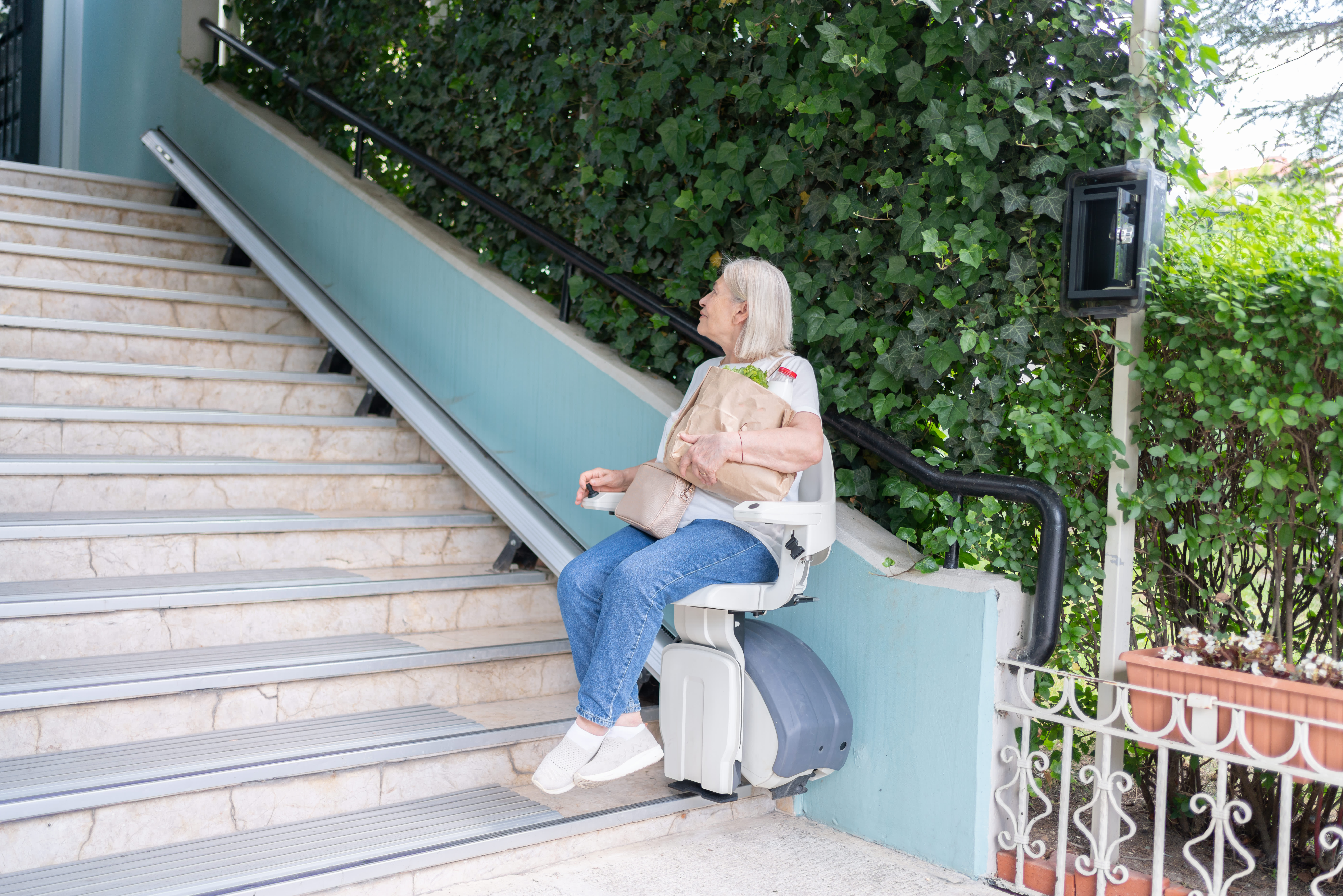 Frau fährt auf einem Außenlift die Treppe hoch.