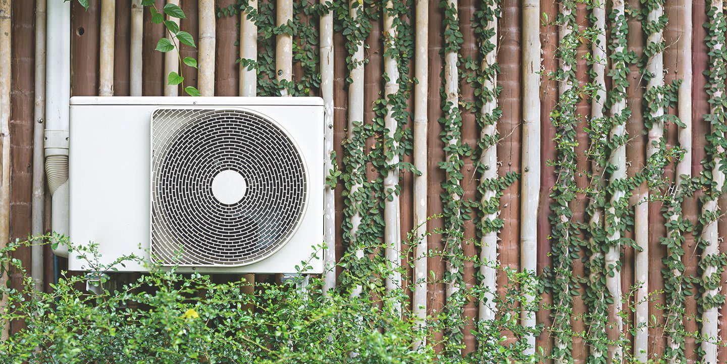 Luftwärmepumpe vor einer bepflanzten Wand