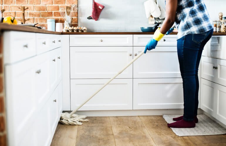 Frau wischt PVC-Boden in der Küche