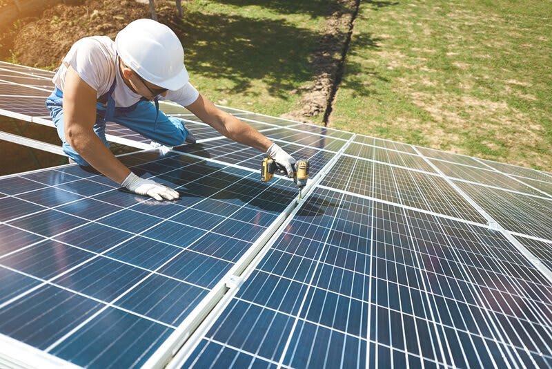 Handwerker montiert eine Solaranlage mit mehreren Solarpanels auf einem Dach