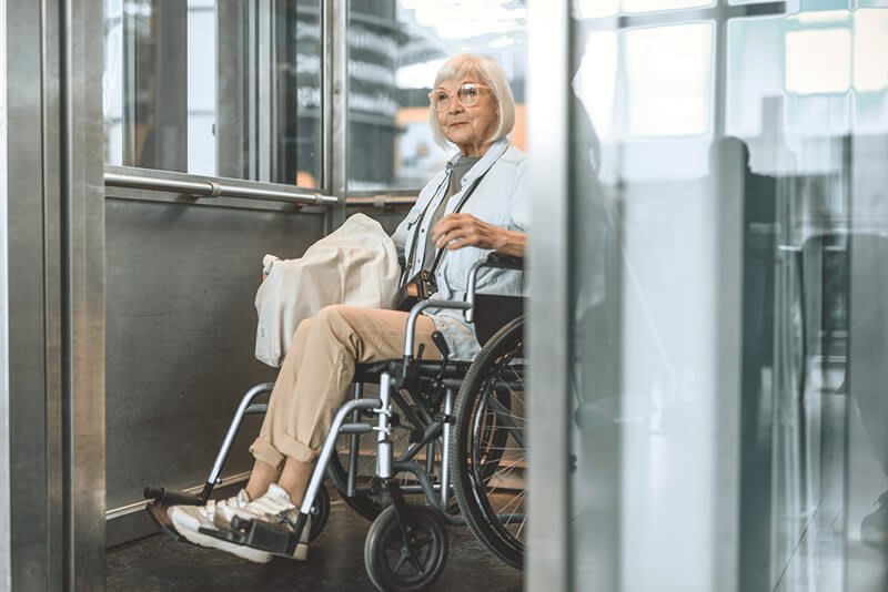 Ältere Frau im Rollstuhl im Aufzug