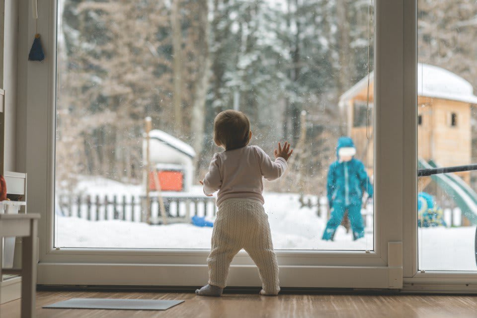 Baby steht an Fenster