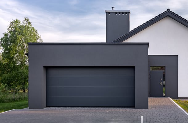 Betongarage mit breitem Tor vor einem Einfamilienhaus