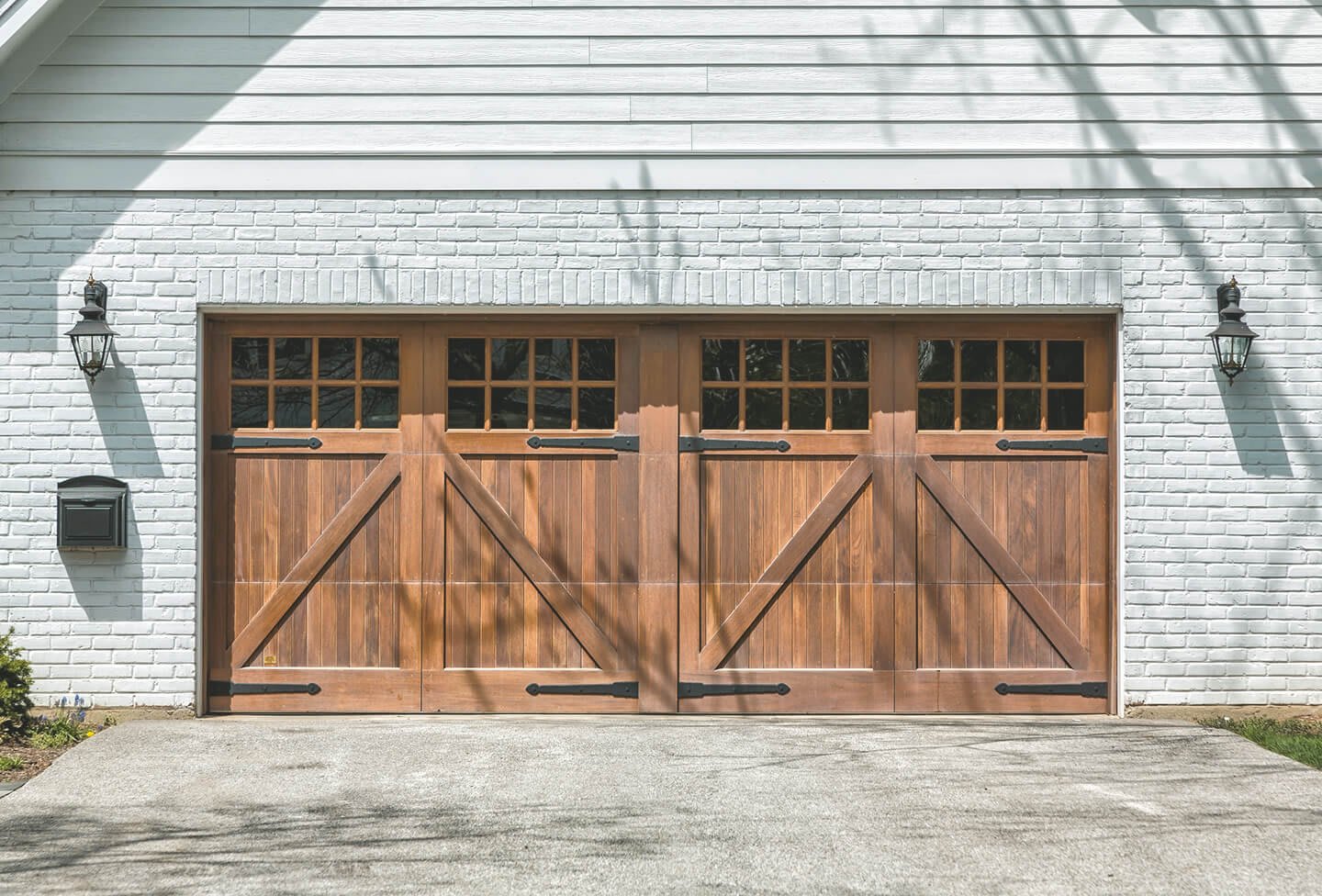 Grau-weiße gemauerte Garage mit breitem Garagentor aus braunem Holz
