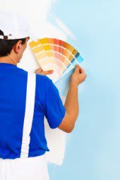 Maler steht vor blauer Wand mit Farbschablone