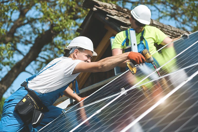 Solarmodule werden auf Dach von Handwerkern montiert