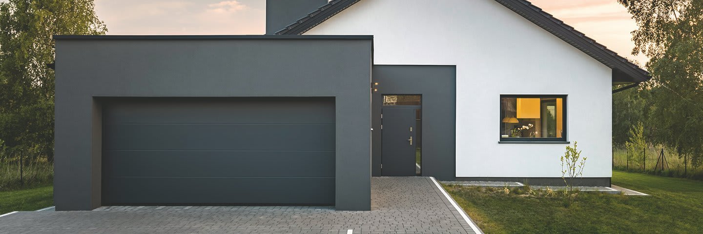Schwarze Beton-Fertiggarage vor einem modernen Einfamilienhaus