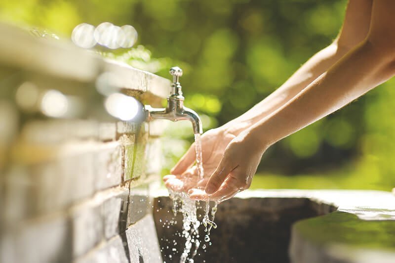 Wasser fließ in Hände am Trinbrunnen