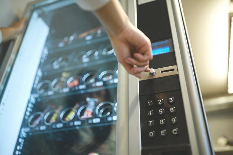 Hand drückt auf Knopf am Warenautomaten