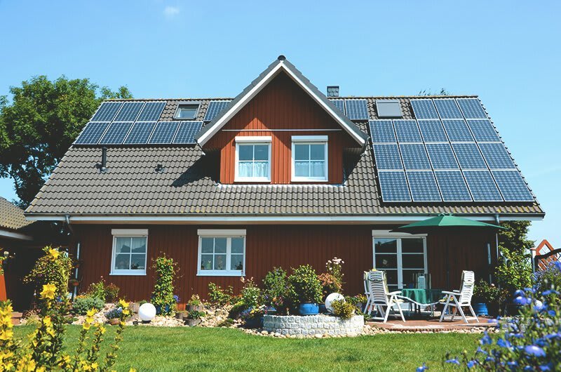 Einfamilienhaus mit sonniger Terrasse und einer Solaranlage auf dem Dach.