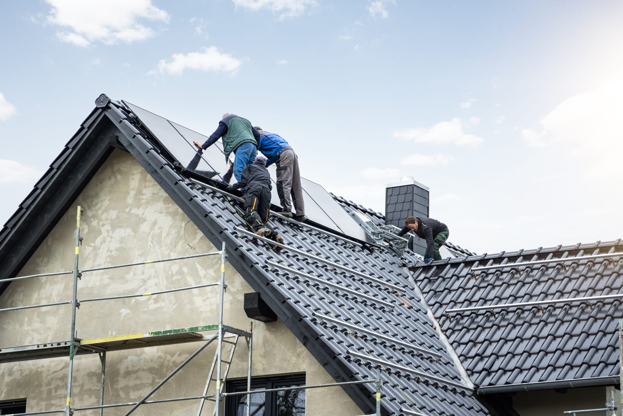 Handwerker montieren Solarpanele auf einem Hausdach.
