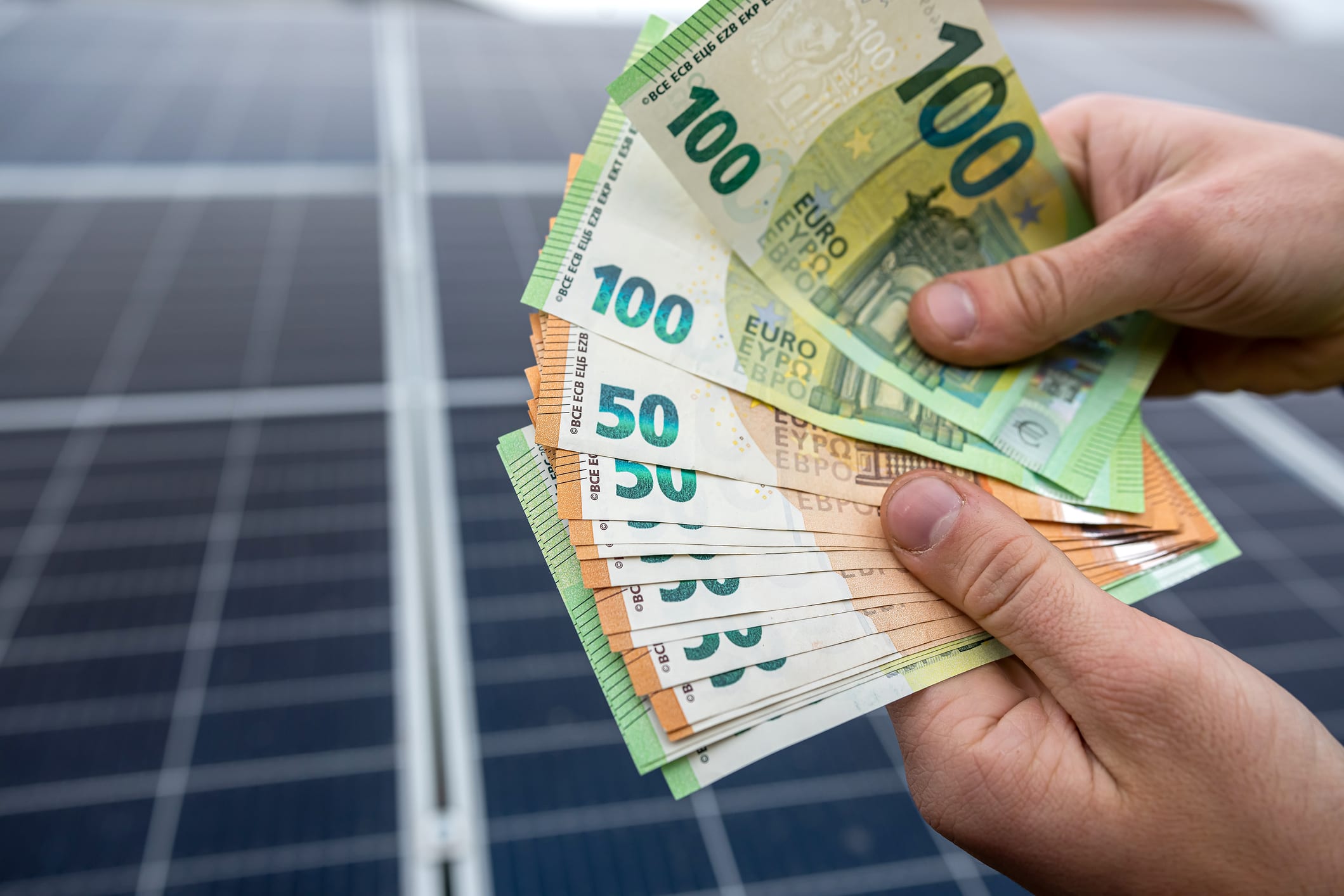 Ein Hauseigentümer zählt vor seiner Solaranlage das Geld das er als Einspeisevergütung erhalten hat.