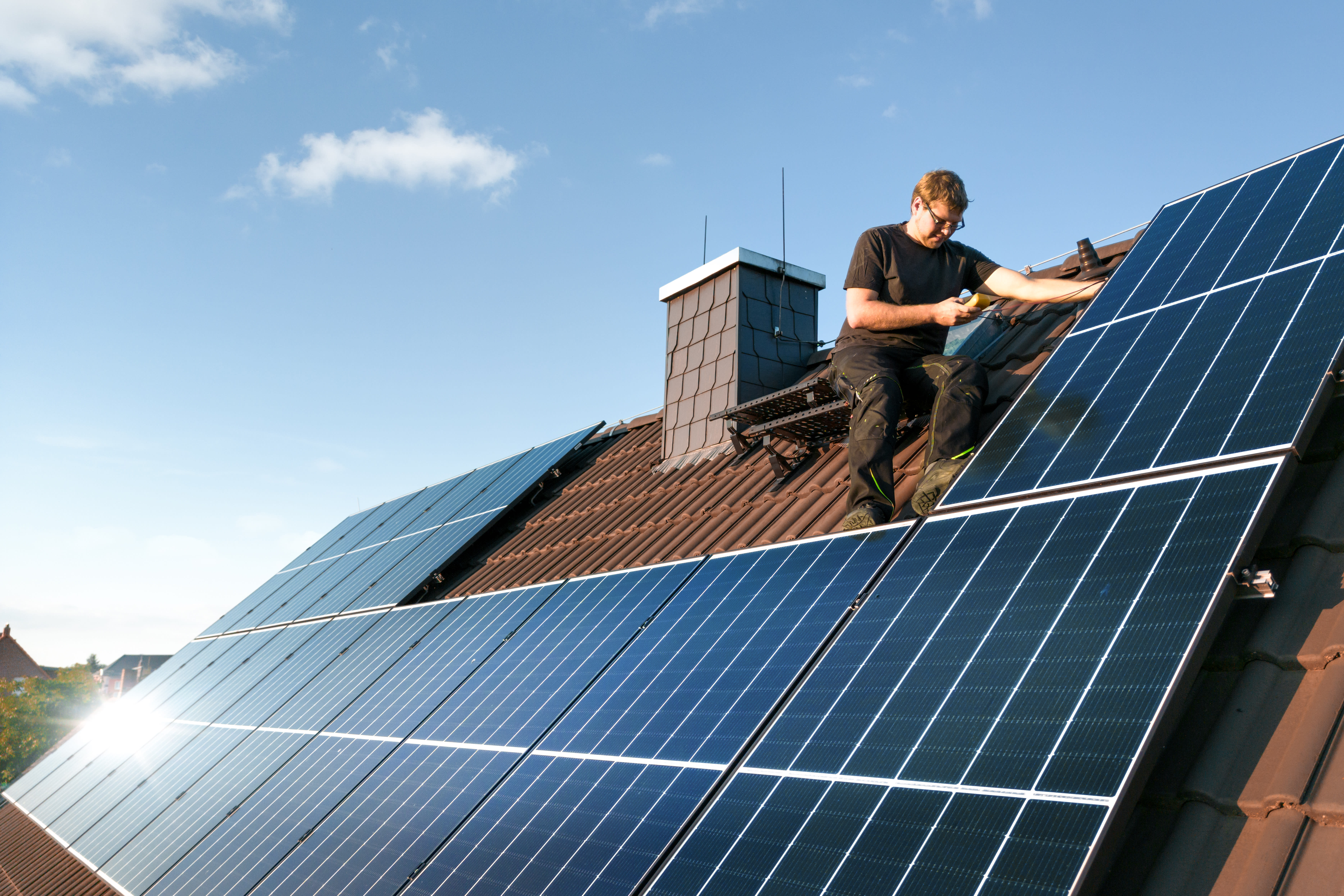 Handwerker installiert Solarmodule auf dem Dach eines Einfamilienhauses