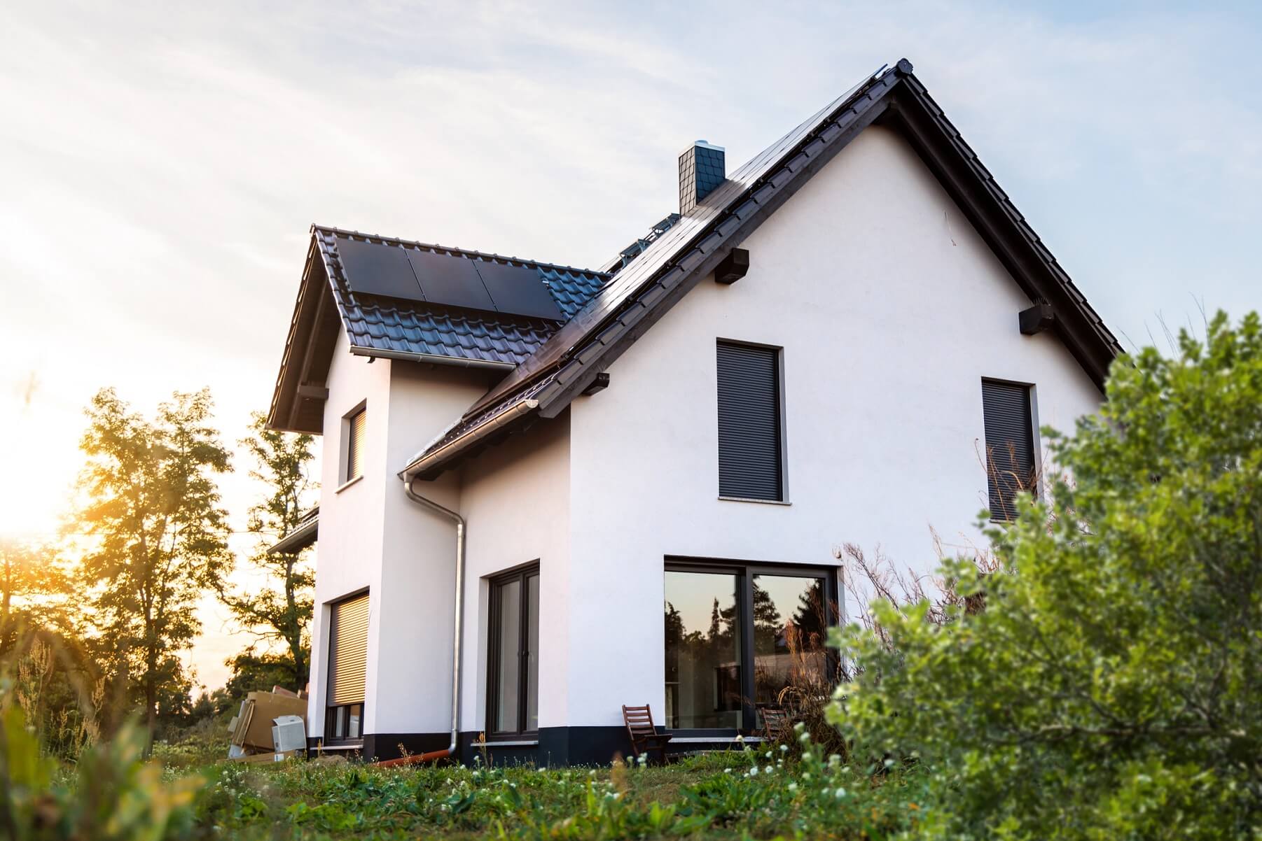 Außenansicht eines neu gebauten Einfamilienhauses in Deutschland. Das Haus ist mit Solarpanelen auf dem Dach ausgestattet und nach modernen Standards der Nachhaltigkeit gebaut.
