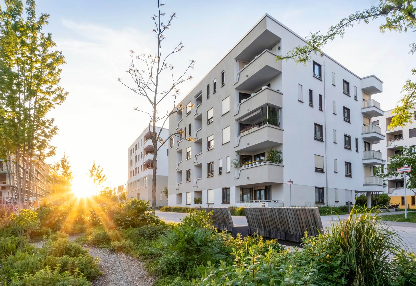 Grünanlage vor einem modernen Mehrfamilienhaus in Deutschland bei Sonnenuntergang