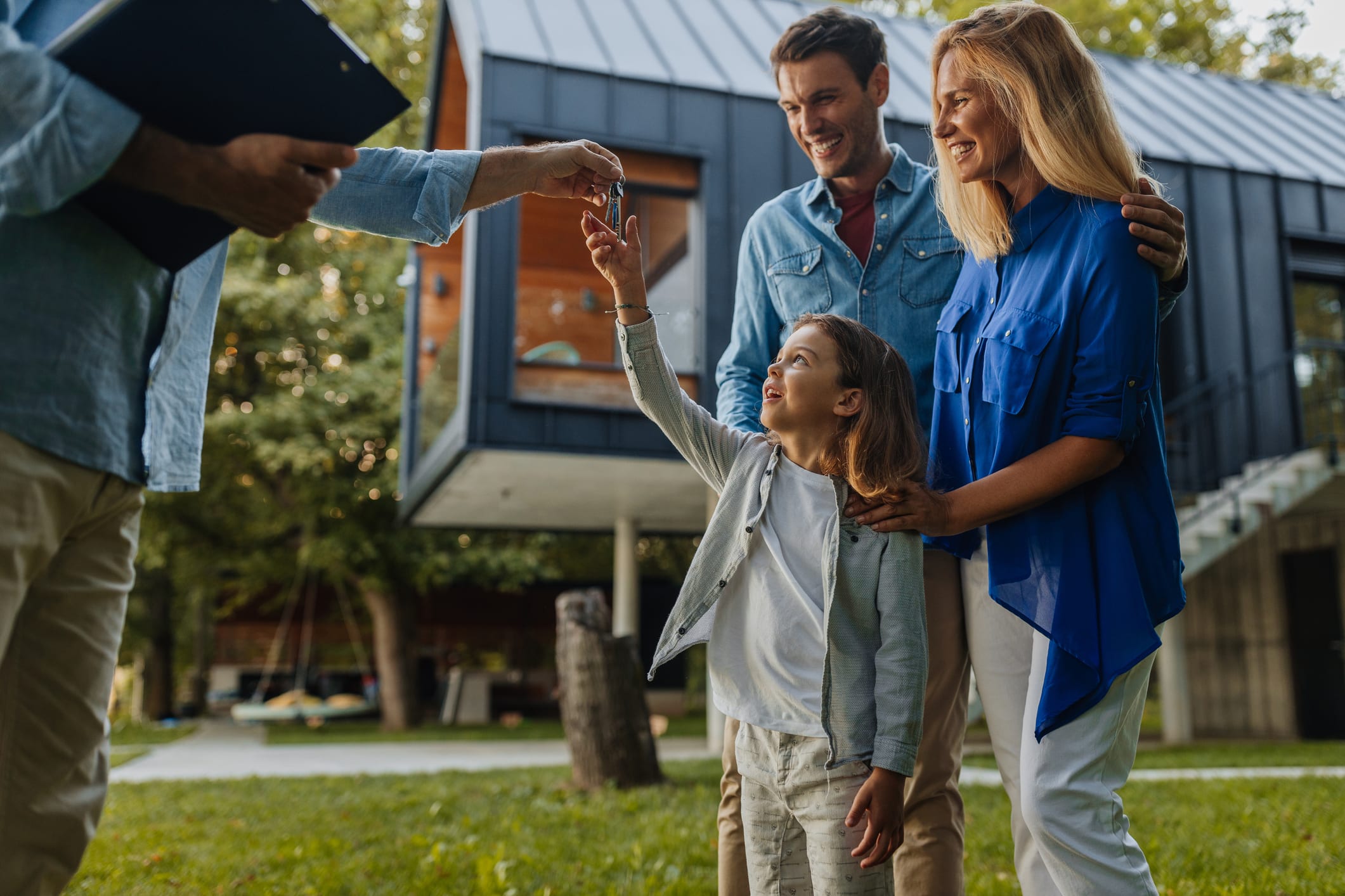 Kind und seine Eltern erhalten Schlüssel für ihr neues Haus von Immobilienmakler
